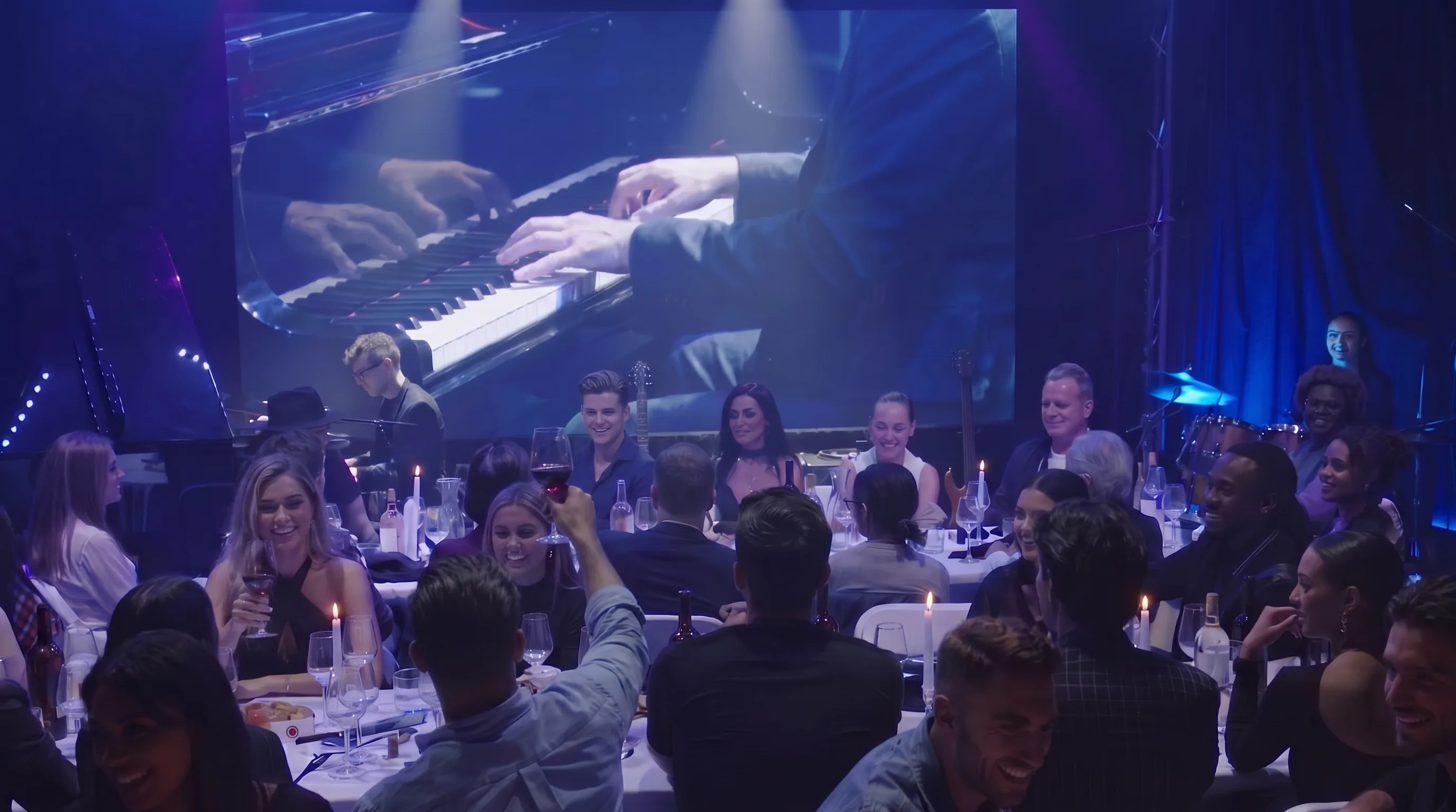 Candlelit tables of guests facing the stage under blue light, the pianist's hands projected on the screen above