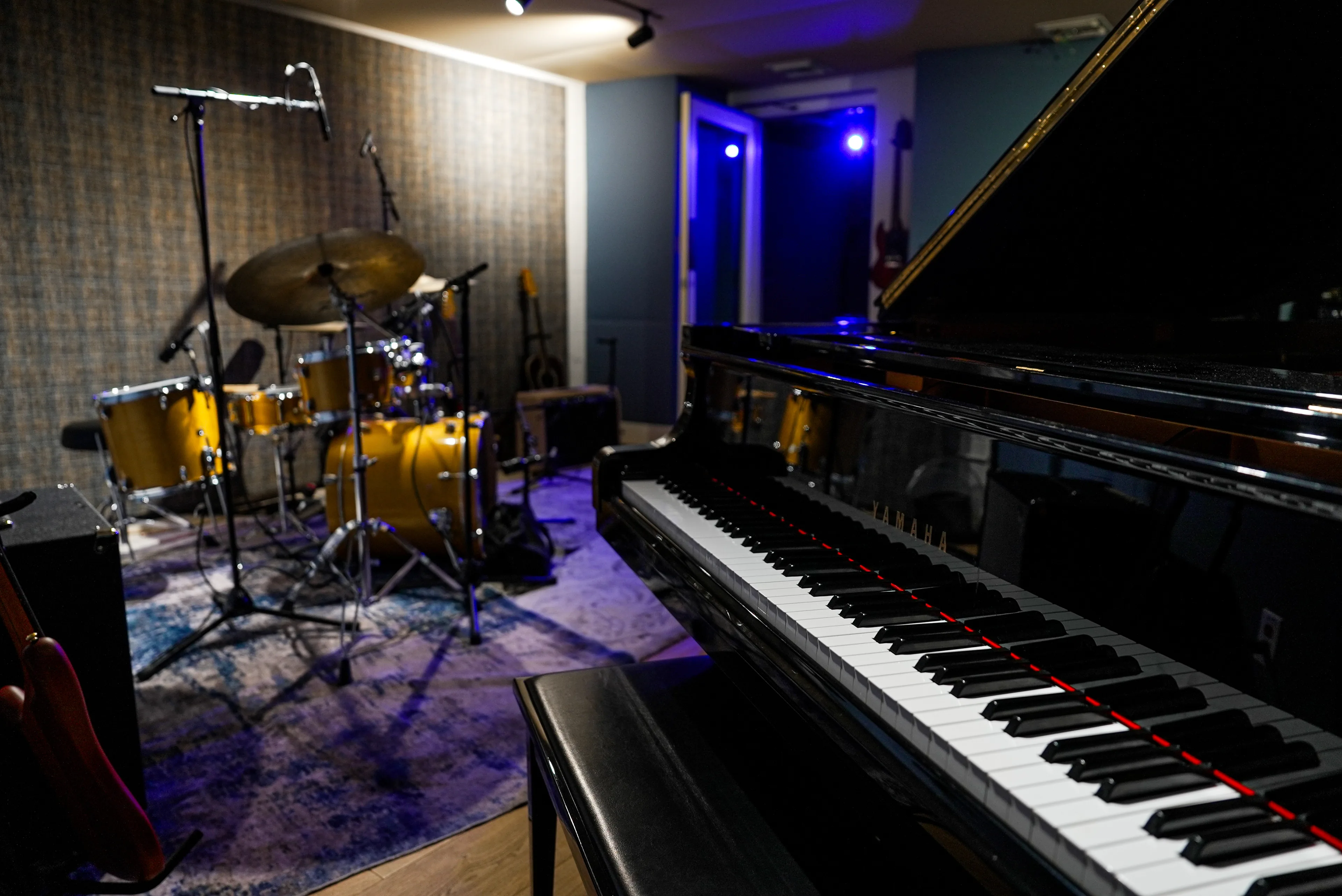 The Recording Room ready for a session: the grand piano in the foreground, the kit mic’d and waiting under blue light