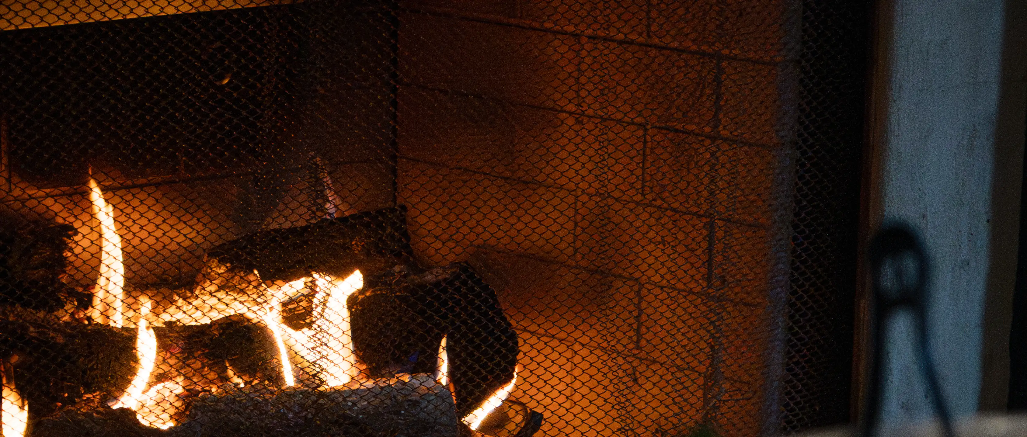 A fire burning low in the club hearth, logs behind the fire screen