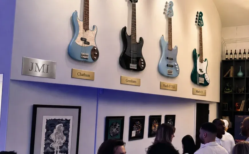 The Jones Musical Instruments wall at the Club, four basses on brass-plaqued mounts above members on the floor