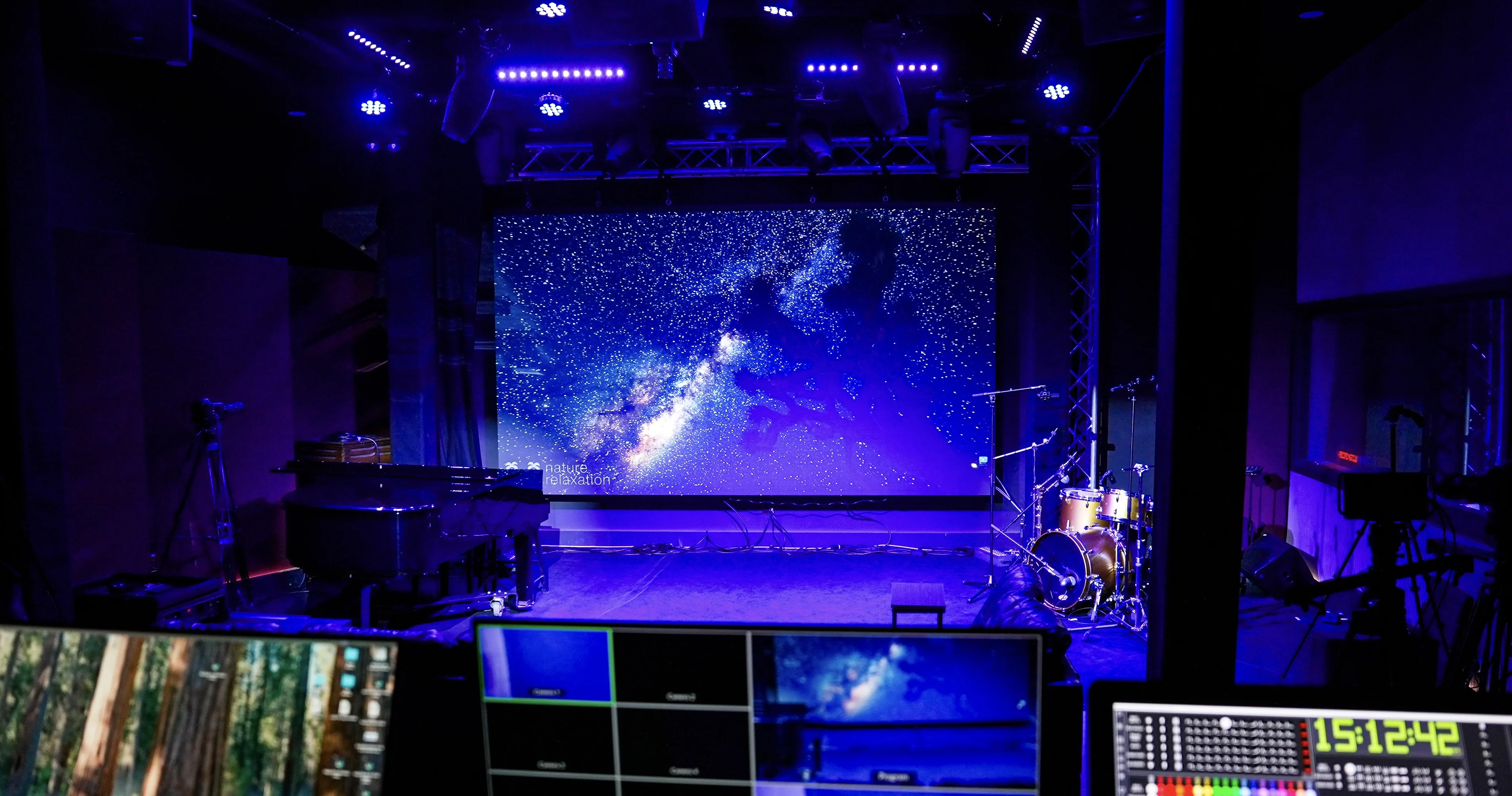 The Live Room in deep blue, the LED wall a field of stars behind the stage, broadcast monitors glowing below