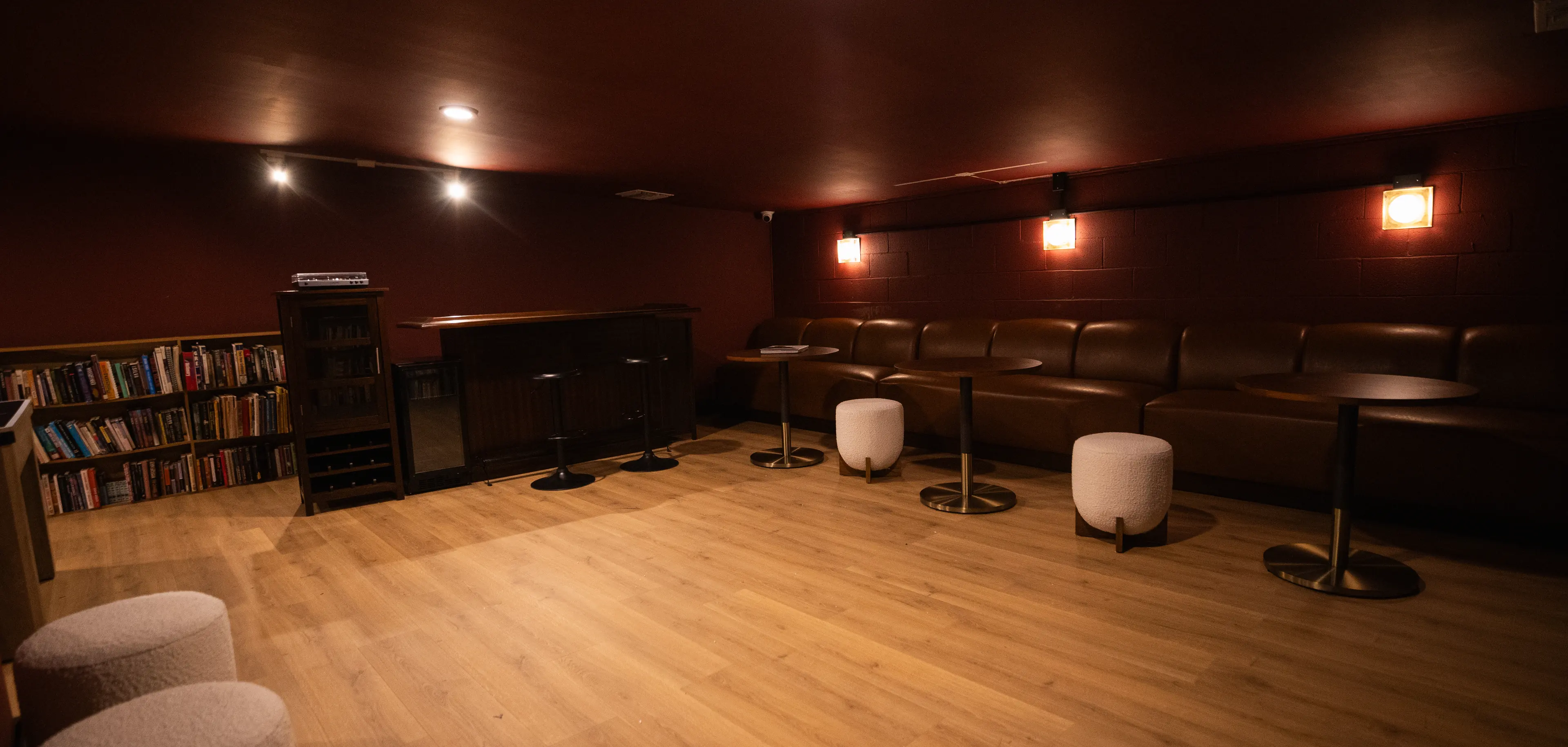 The lounge at dusk: banquette seating along the red library wall, the bar lit at the far end