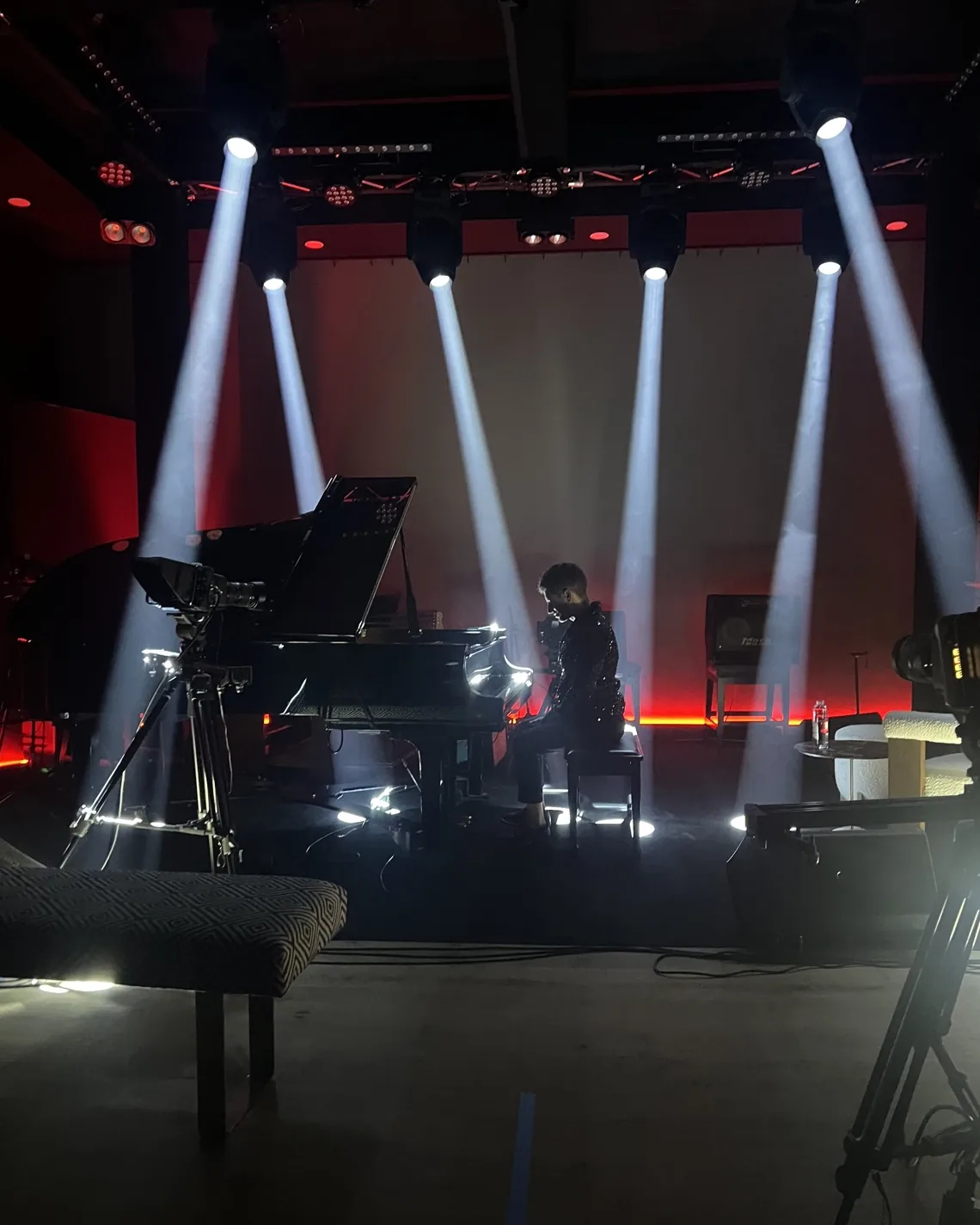 A pianist alone at the grand on the Live Room stage, five beams of light cutting through the haze