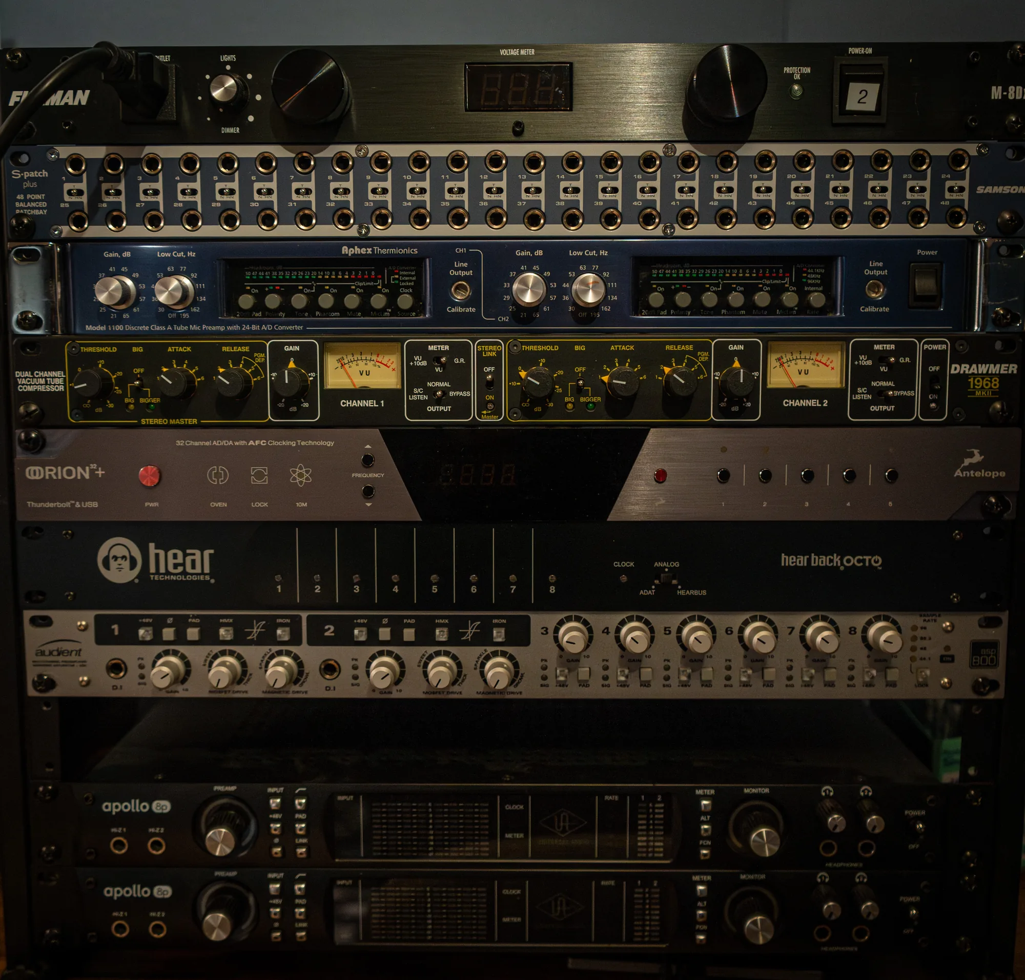 A rack of outboard gear, preamps and tube compressors and converters, meters lit