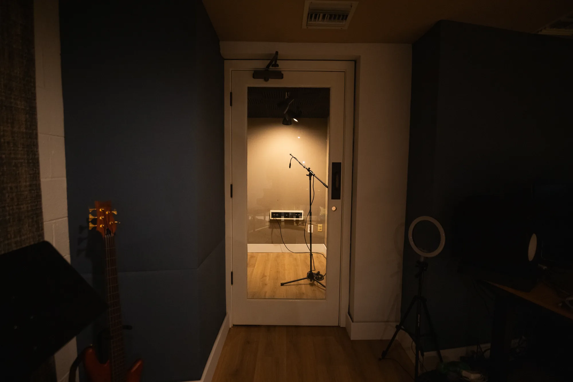 The door of the isolated vocal booth standing open, a microphone waiting inside